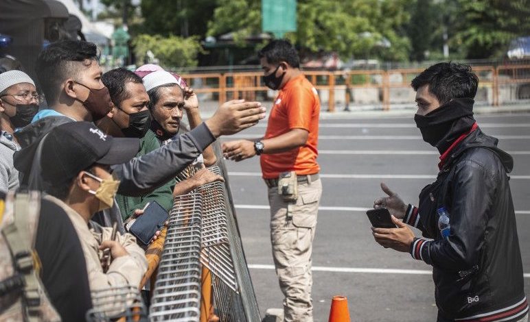 Petugas memberikan imbauan kepada warga yang akan berwisata untuk kembali pulang di depan pintu masuk Ancol Taman Impian, Jakarta, Sabtu (15/5/2021). Foto : Antara/Aprillio Akbar/wsj.