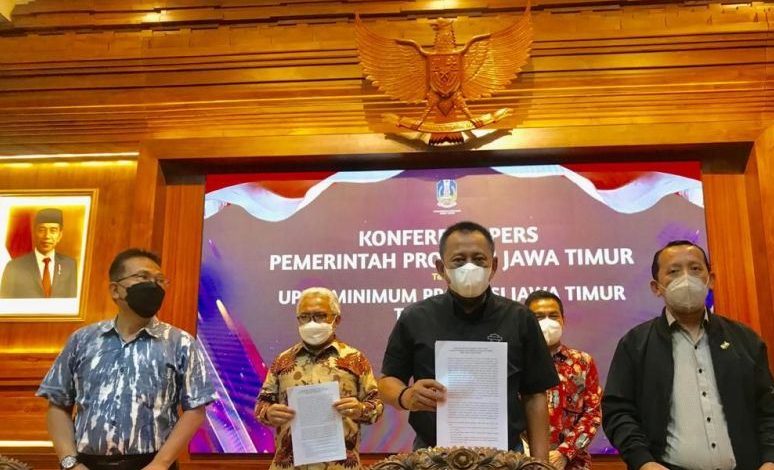 Plh Sekdaprov Jatim Heru Tjahjono (tengah) menunjukkan SK Gubenur Jatim Nomor : 188/783/KPTS/013/2021 tanggal 20 Nopember 2021 tentang Upah Minimum Jawa Timur 2022 usai menggelar konferensi pers di Gedung Negara Grahadi di Surabaya, Minggu (21/11/2021) malam. Foto : Antara/Fiqih Arfani