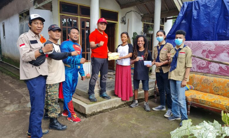 Koordinator Tim Relawan Korban Semeru dari AKBM (Anak Korps Baret Merah) Susilo (empat kiri) memberikan bantuan kepada sorang ibu yang suaminya mengalami luka bakar akibat terkena awan panas Semeru. Foto : AKBM
