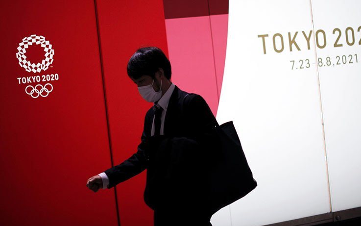 Seorang pria yang mengenakan masker pelindung berjalan melewati iklan Olimpiade Tokyo 2020 yang telah ditunda hingga 2021 karena wabah Covid-19 di Tokyo, Jepang, 22 Januari 2021. Foto : Antara/Reuters /Issei Kato/pri.
