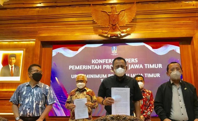 Plh Sekdaprov Jatim Heru Tjahjono (tengah) menunjukkan SK Gubenur Jatim Nomor : 188/783/KPTS/013/2021 tanggal 20 Nopember 2021 tentang Upah Minimum Jawa Timur 2022 usai menggelar konferensi pers di Gedung Negara Grahadi di Surabaya, Minggu (21/11/2021) malam. Foto : Antara/Fiqih Arfani
