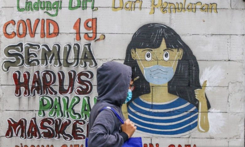 Warga melintas di dekat mural bertemakan Covid-19 di Petamburan, Jakarta, Rabu (21/7/2021). Foto: Antara/Rivan Awal Lingga/foc.