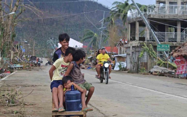 Anak-anak naik kereta darurat di dekat jalan yang rusak di Provinsi Surigao del Norte, Filipina, Sabtu (18/12/2021). Foto : Antara /Philippine Coast Guard/Handout via Reuters/rwa.