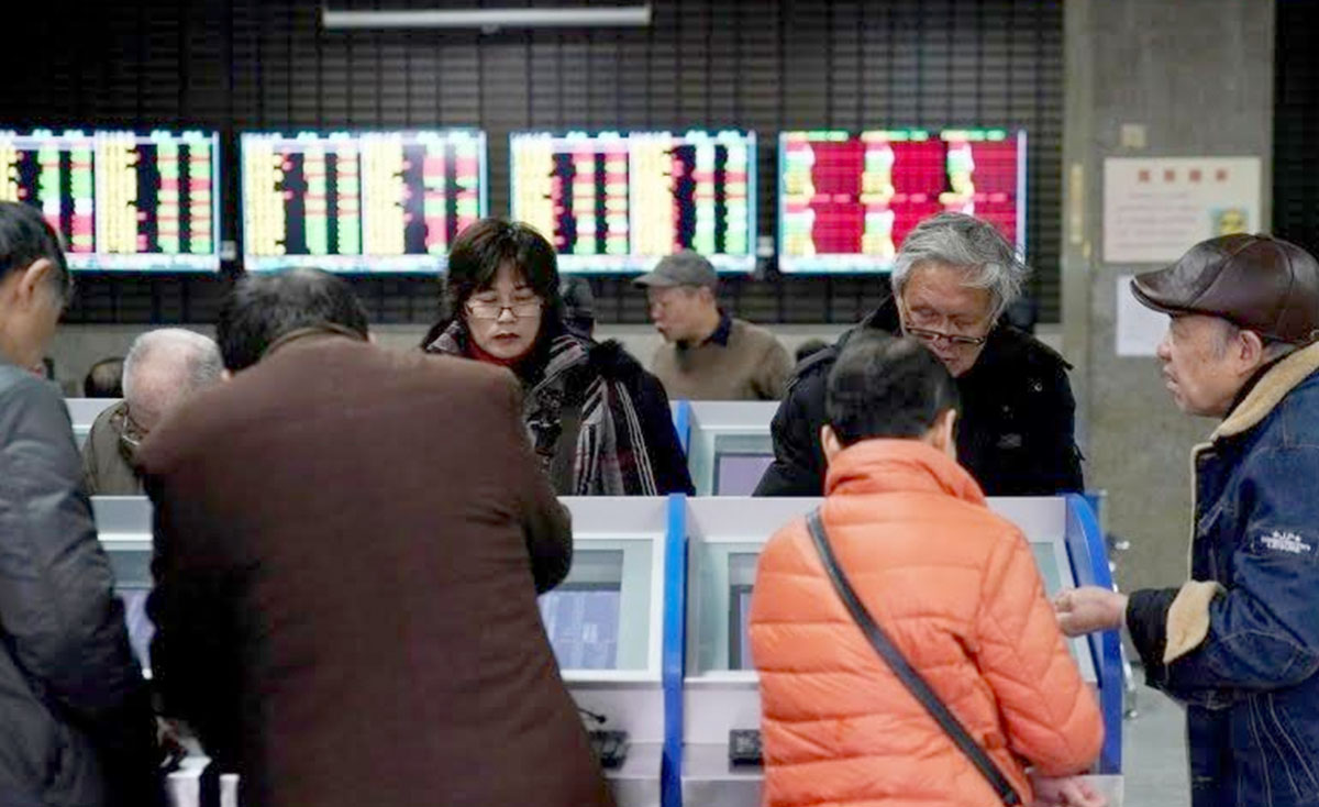Investor melihat layar komputer yang menampilkan informasi saham di sebuah rumah pialang di Shanghai, China.