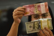 Ilustrasi - Pegawai menunjukkan mata uang rupiah dan dolar AS di salah satu gerai penukaran mata uang di Jakarta