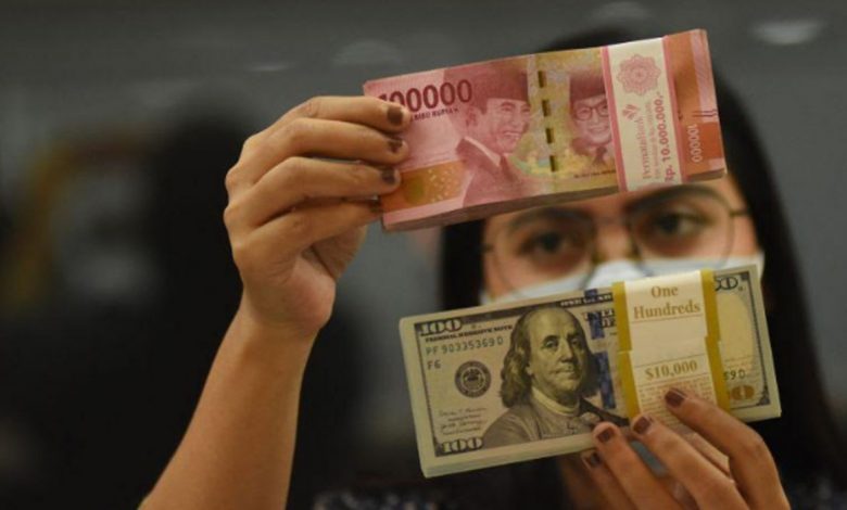 Ilustrasi - Pegawai menunjukkan mata uang rupiah dan dolar AS di salah satu gerai penukaran mata uang di Jakarta