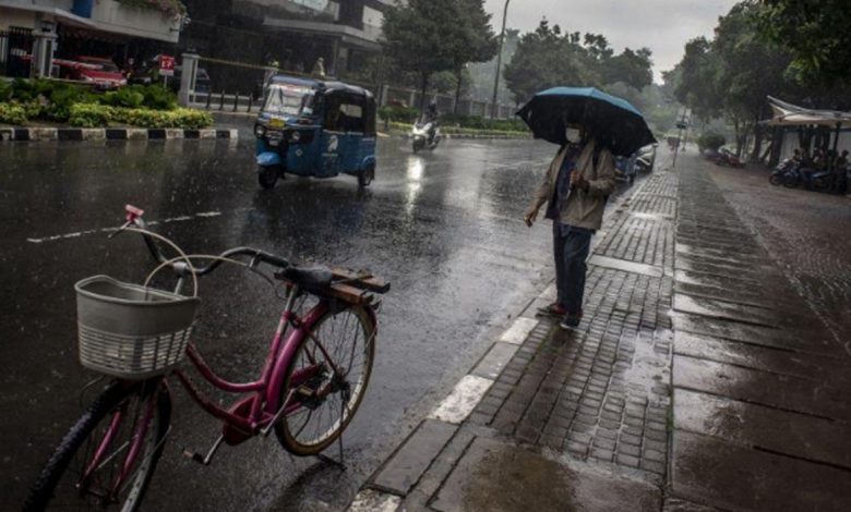 Warga berjalan menggunakan payung saat hujan di kawasan Kelurahan Gambir, Jakarta, Kamis