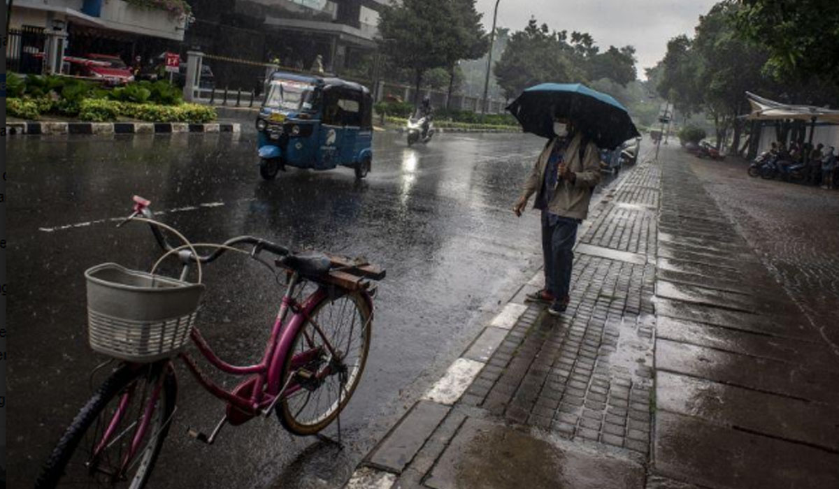 Warga berjalan menggunakan payung saat hujan di kawasan Kelurahan Gambir, Jakarta, Kamis