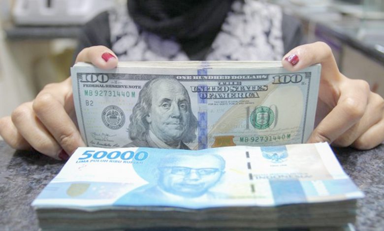 Pekerja menunjukkan uang dolar AS dan rupiah di salah satu gerai penukaran mata uang