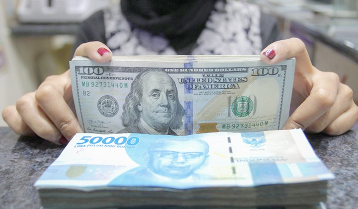 Pekerja menunjukkan uang dolar AS dan rupiah di salah satu gerai penukaran mata uang