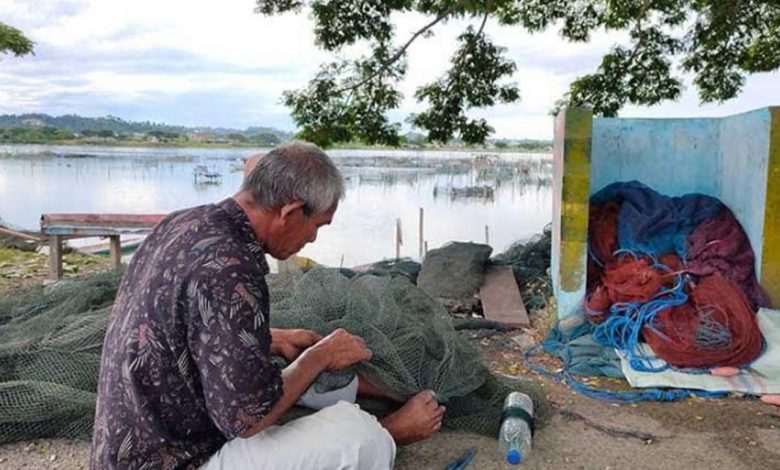 Nazaruddin Razali, nelayan yang mengajukan permohonan suntik mati, sedang memperbaiki jaring keramba di Waduk Pusong, Lhokseumawe,
