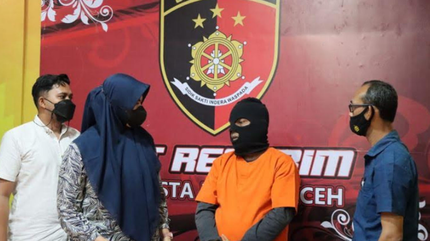 Terduga pelaku pemerkosa dan pelecehan seksual terhadap anak tirinya berinisial SB (baju oranye) saat ditanyai oleh kepolisian, di Mapolresta Banda Aceh, Kamis (6/1/2022)