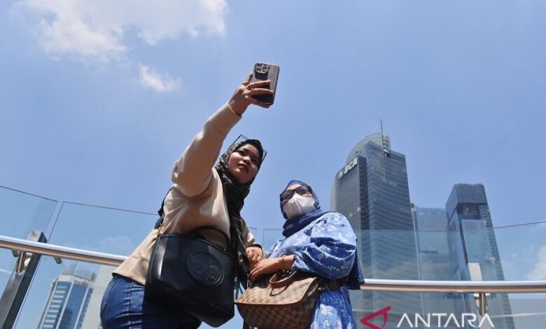 Arsip Foto - Warga berswafoto dengan latar belakang gedung dan langit biru di kawasan Bundaran HI, Jakarta, Selasa (12/9/2023). ANTARA